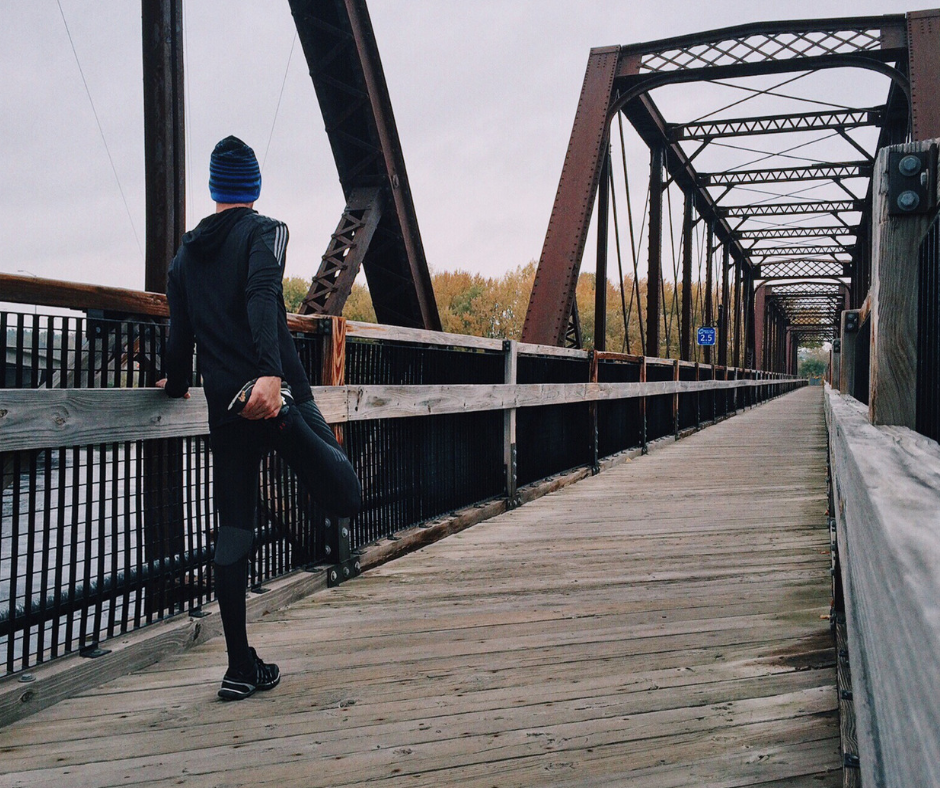 A person stretching before going on a run across a bridge