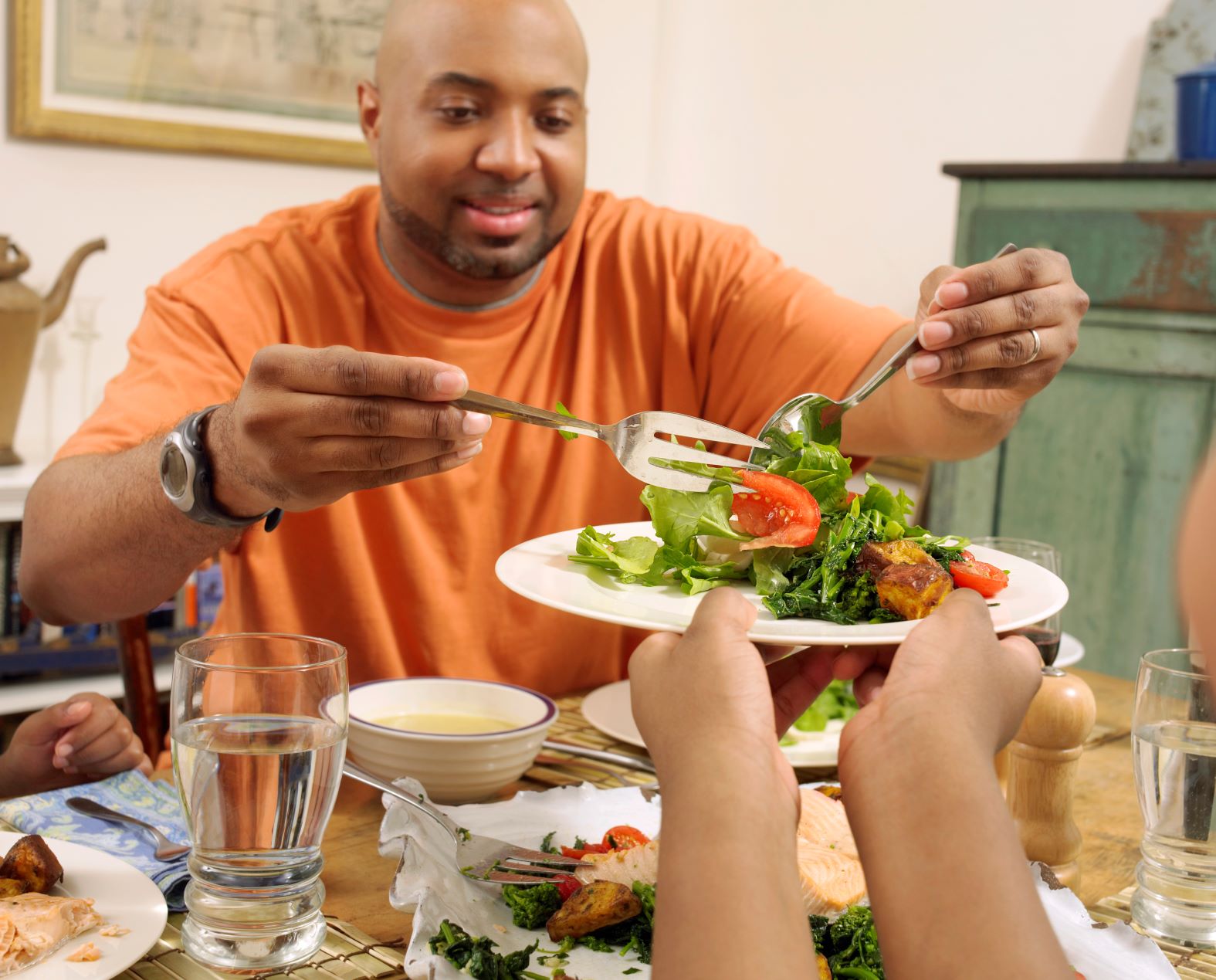 A man serving another person salad onto their plate