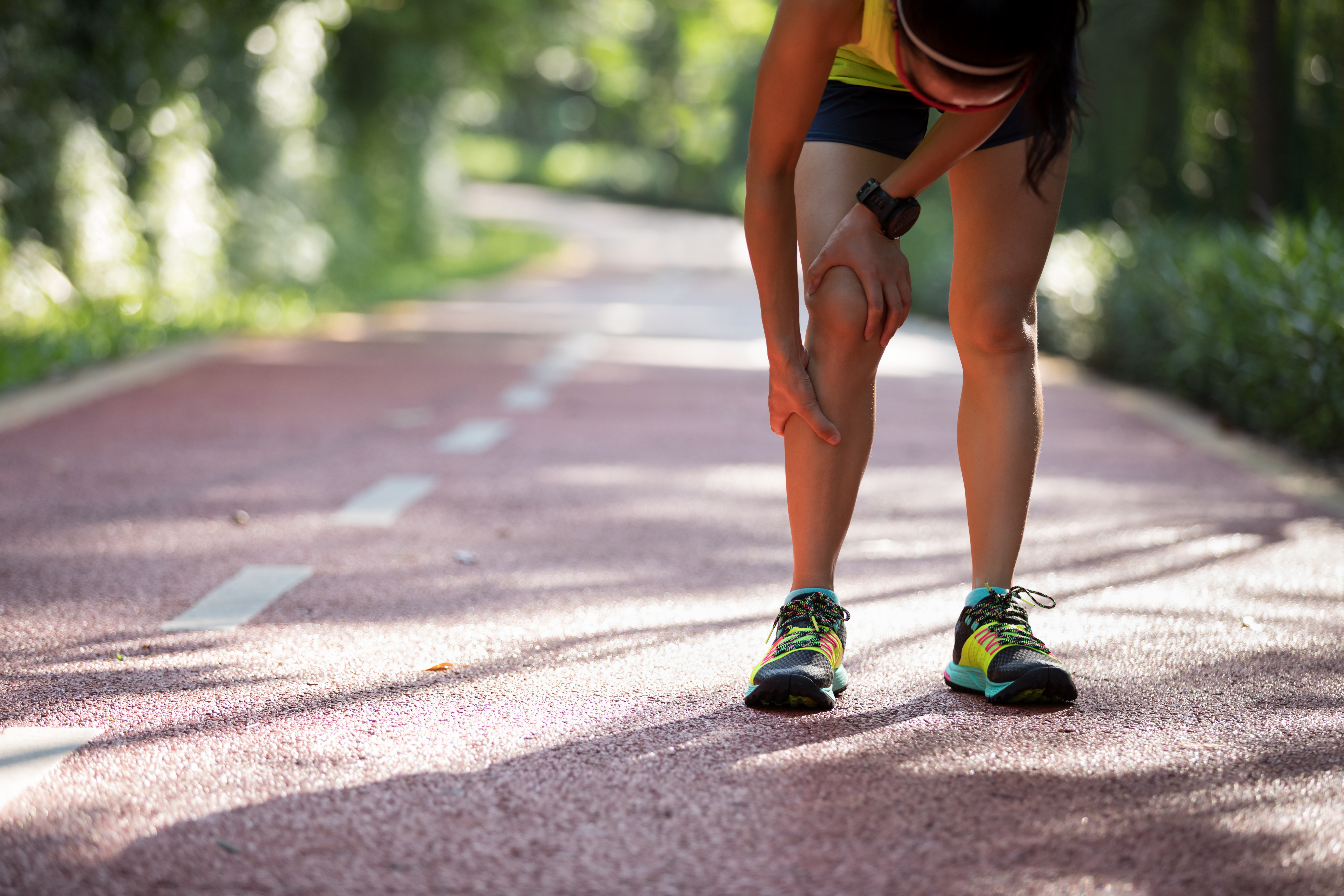 Female runner bent down with shin splints