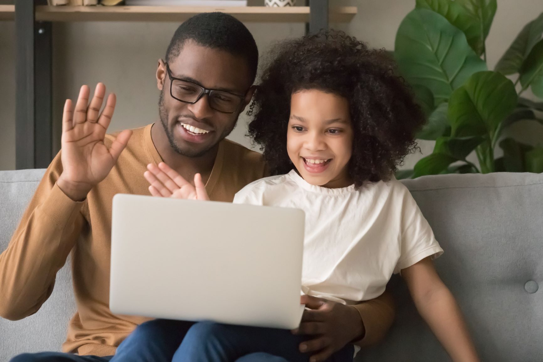 Father and daughter waving to a laptop screen