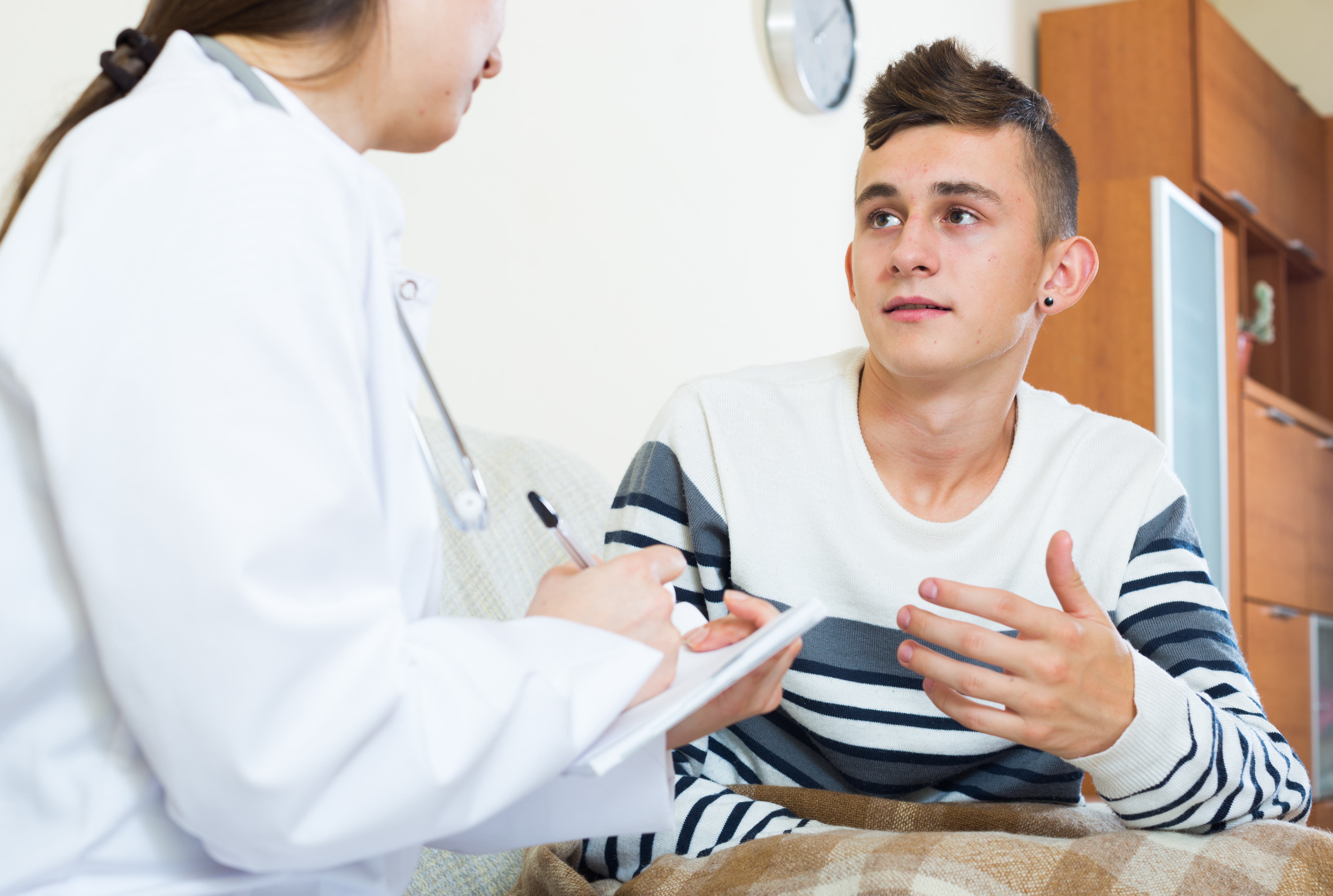 A young person in a healthcare facility talking to a doctor