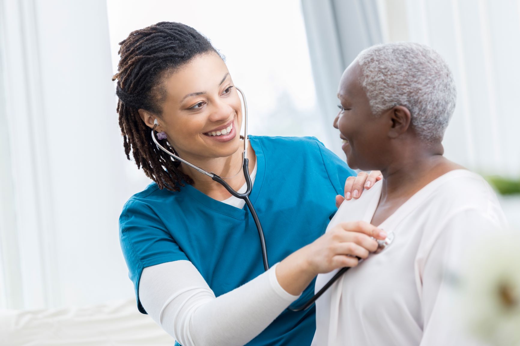 Female nurse listening to an older female's chest