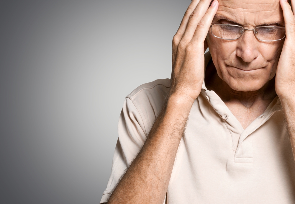 An older man holding his head in his hands