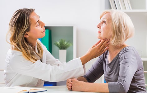 A speech language pathologist working with a patient, touching their throat