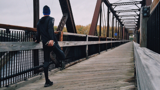 man stretching on a bridge in running gear