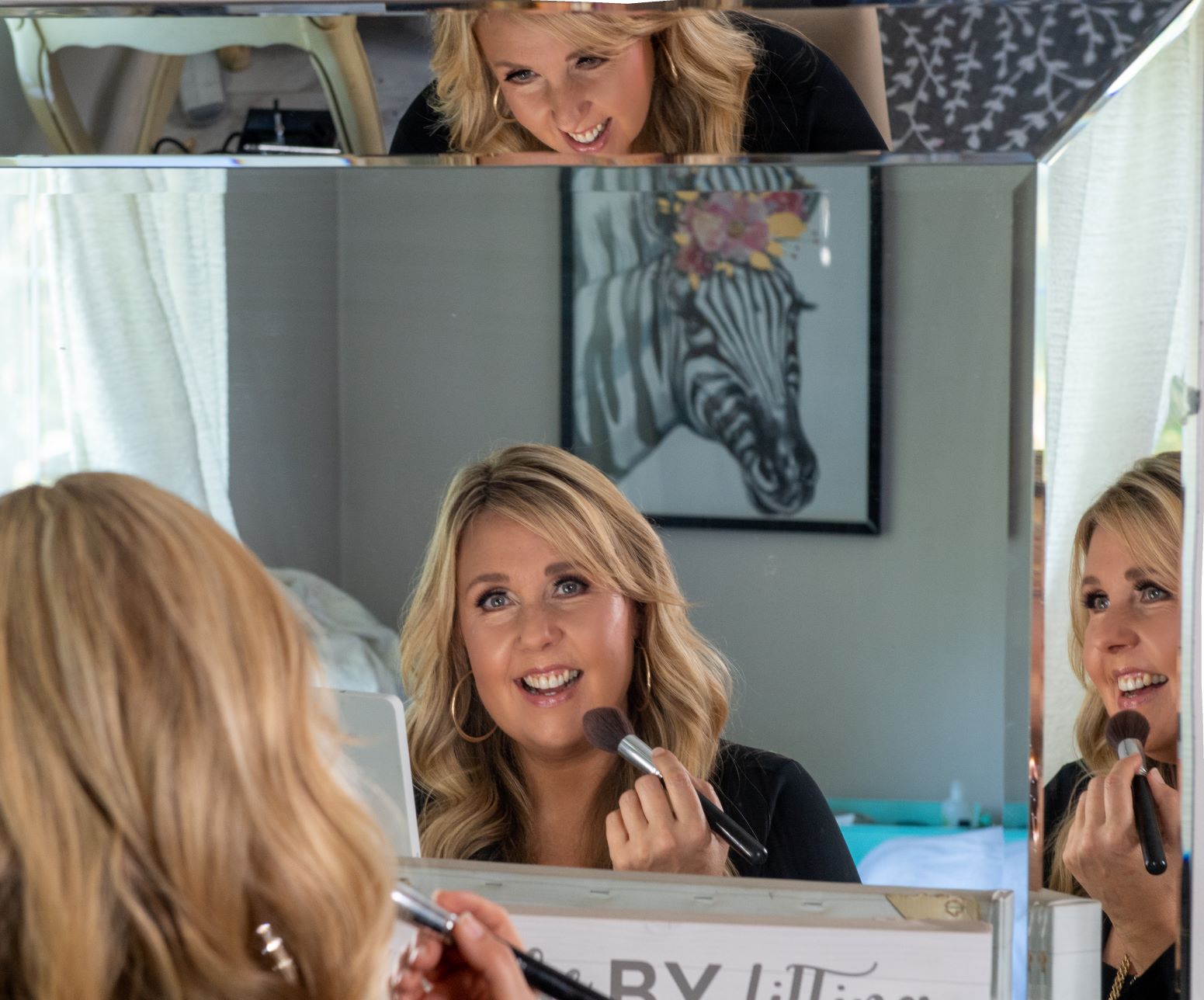 karen mcgowen smiling into a mirror while applying makeup