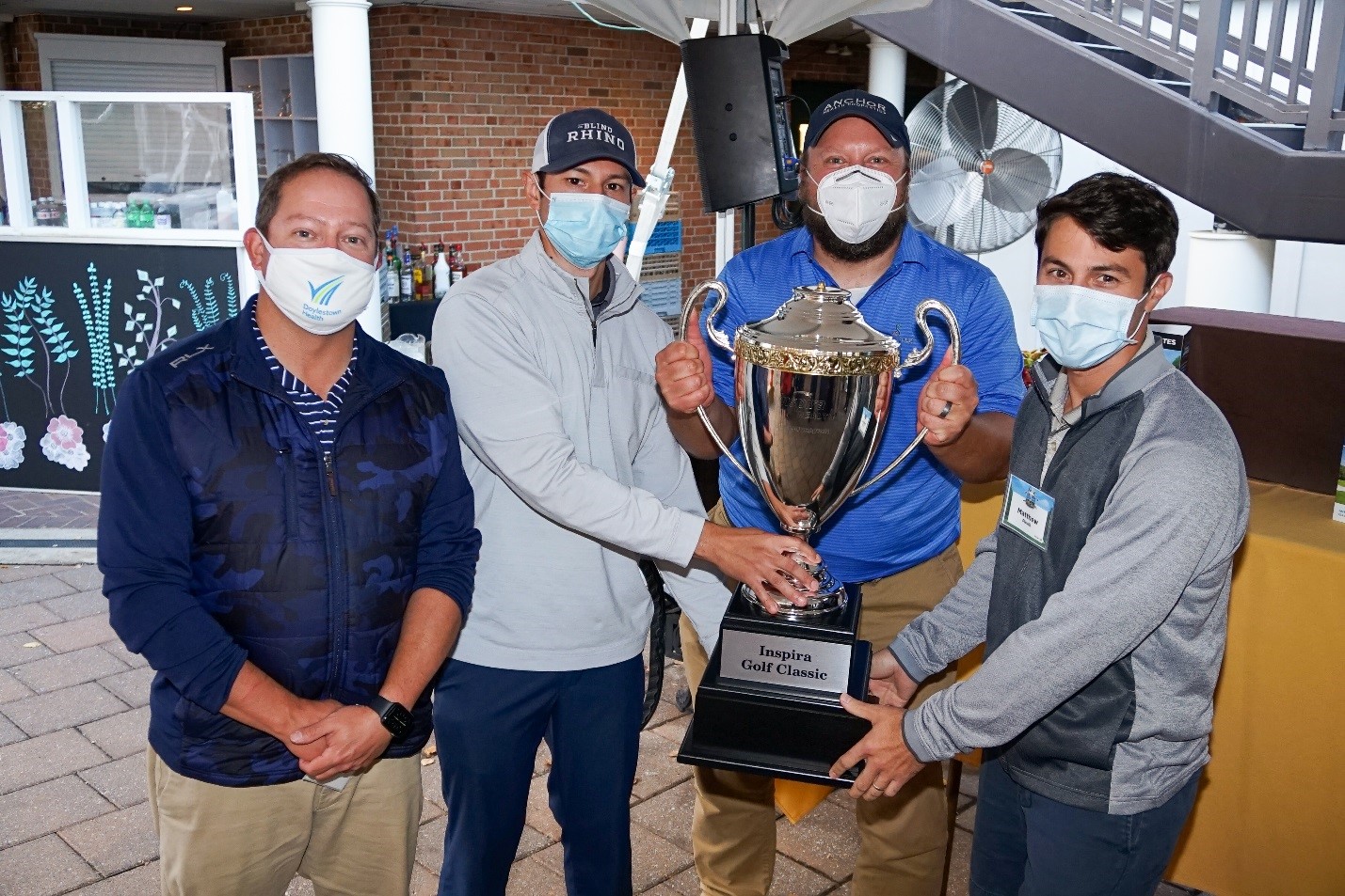 Group of men holding a trophy while wearing medical masks