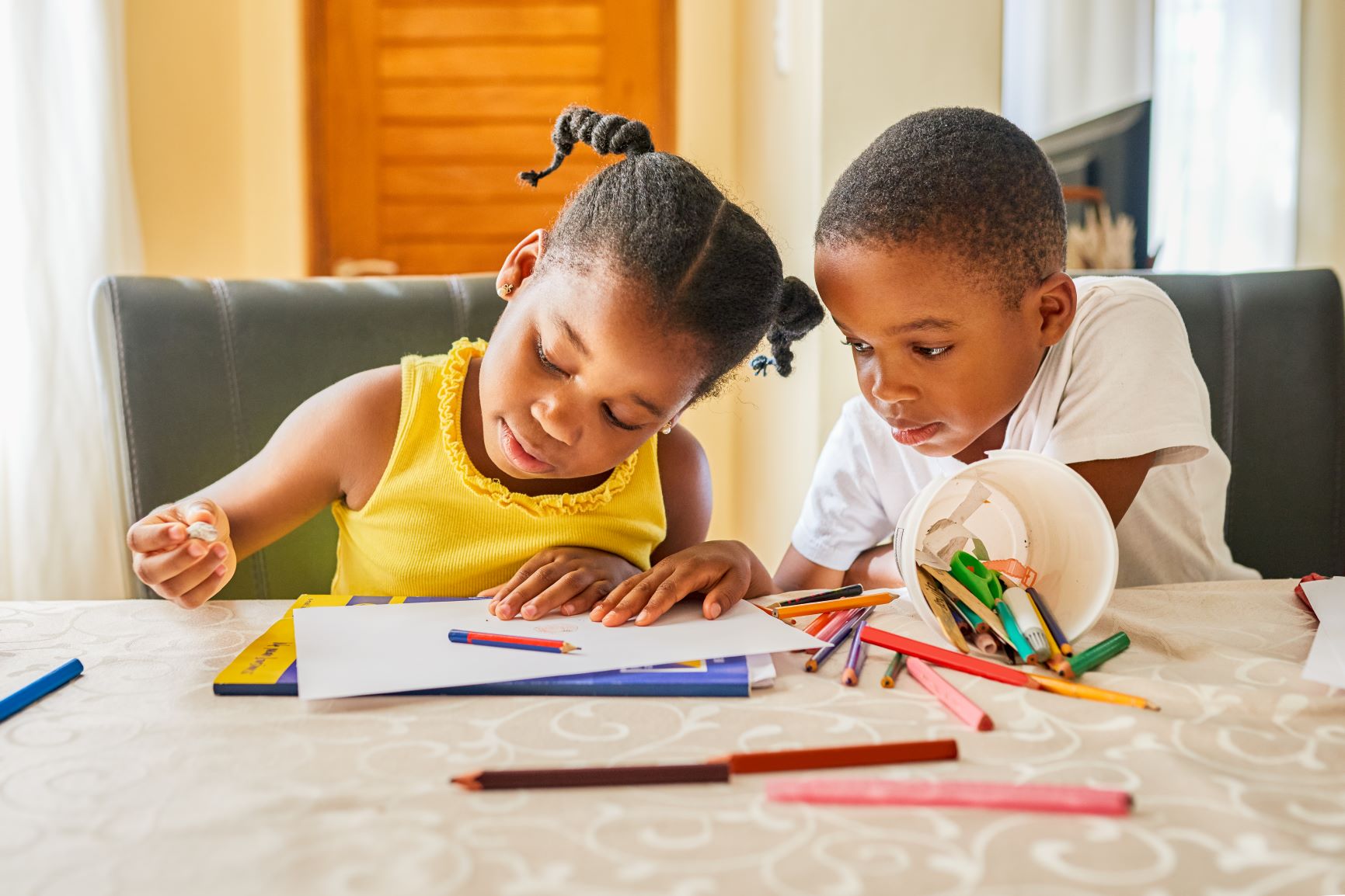Shot of a little boy watching his sister as she does her homework