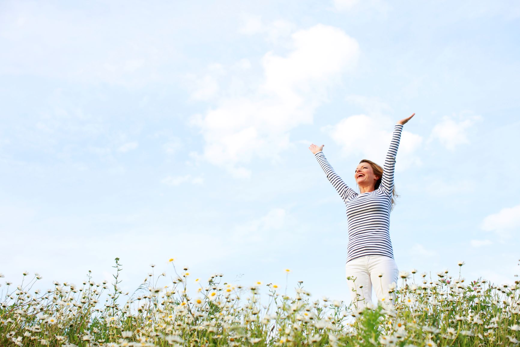 woman standing in a flower field with her hands held above her head