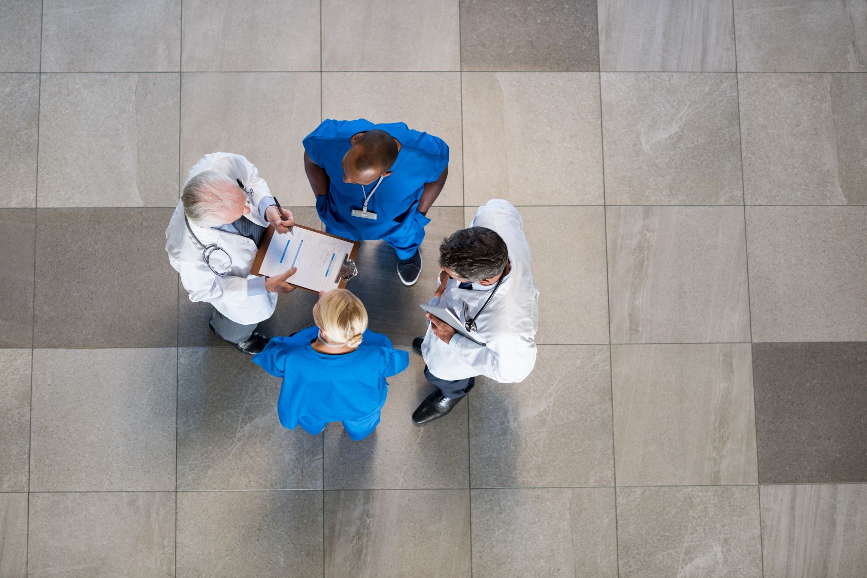 High angle view of senior doctors and young surgeons discussing over patient case. Top view of group of doctor in a conversation with copyspace. Doctors and nurses talking to each other about medical results.