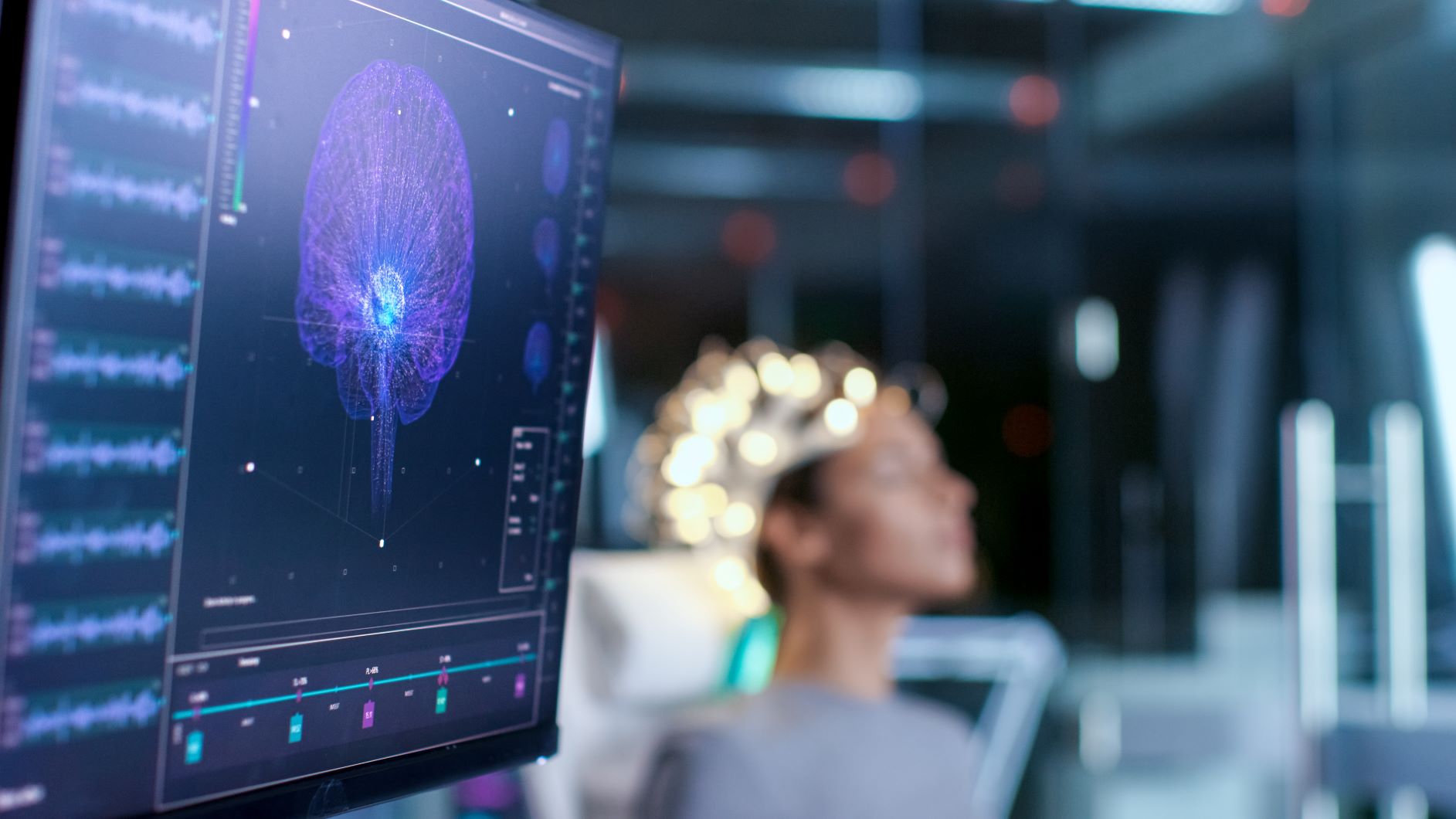 woman with electrodes on her head and a screen measuring brain activity