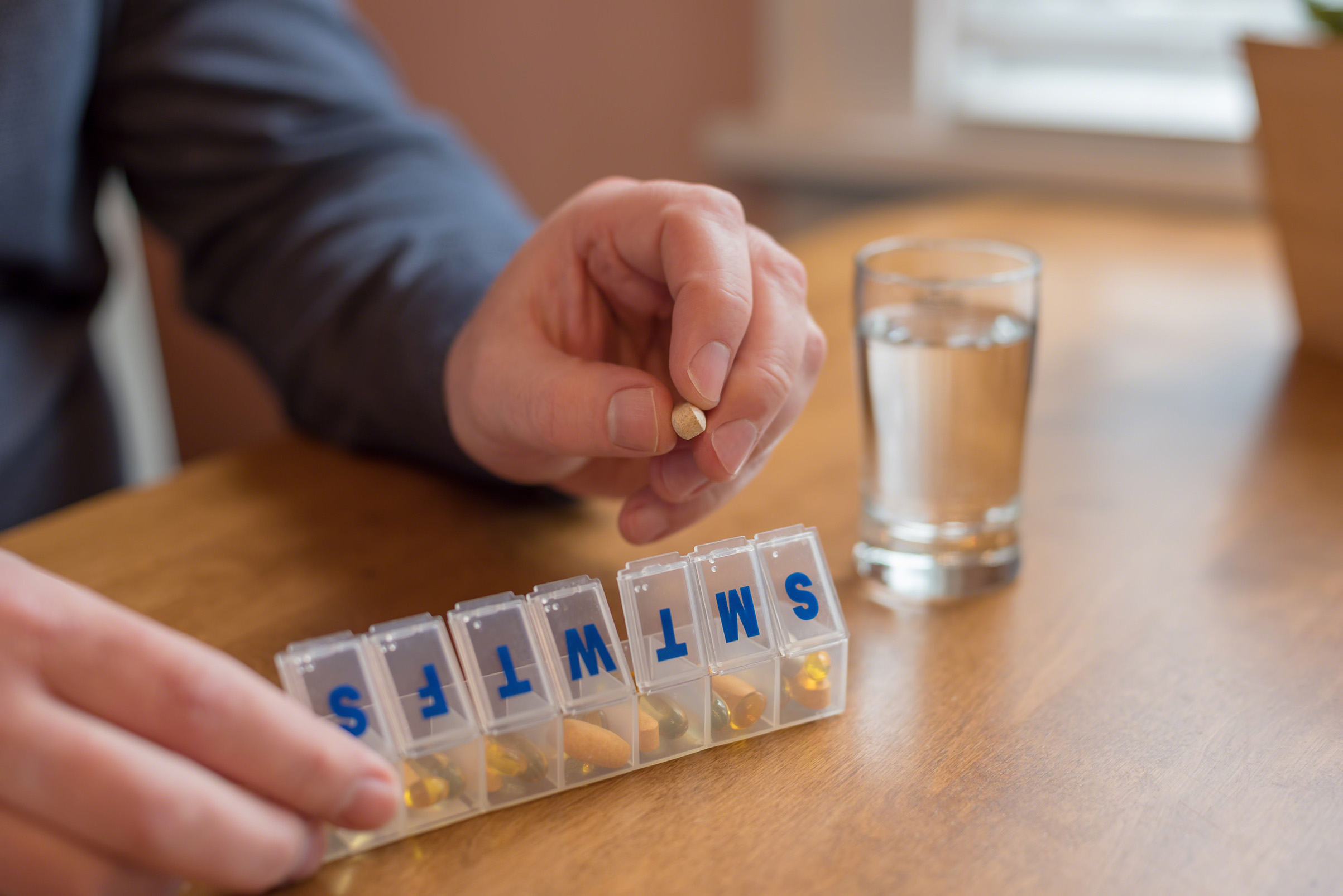Man using a pill holder for daily meds, vitamins and supplements