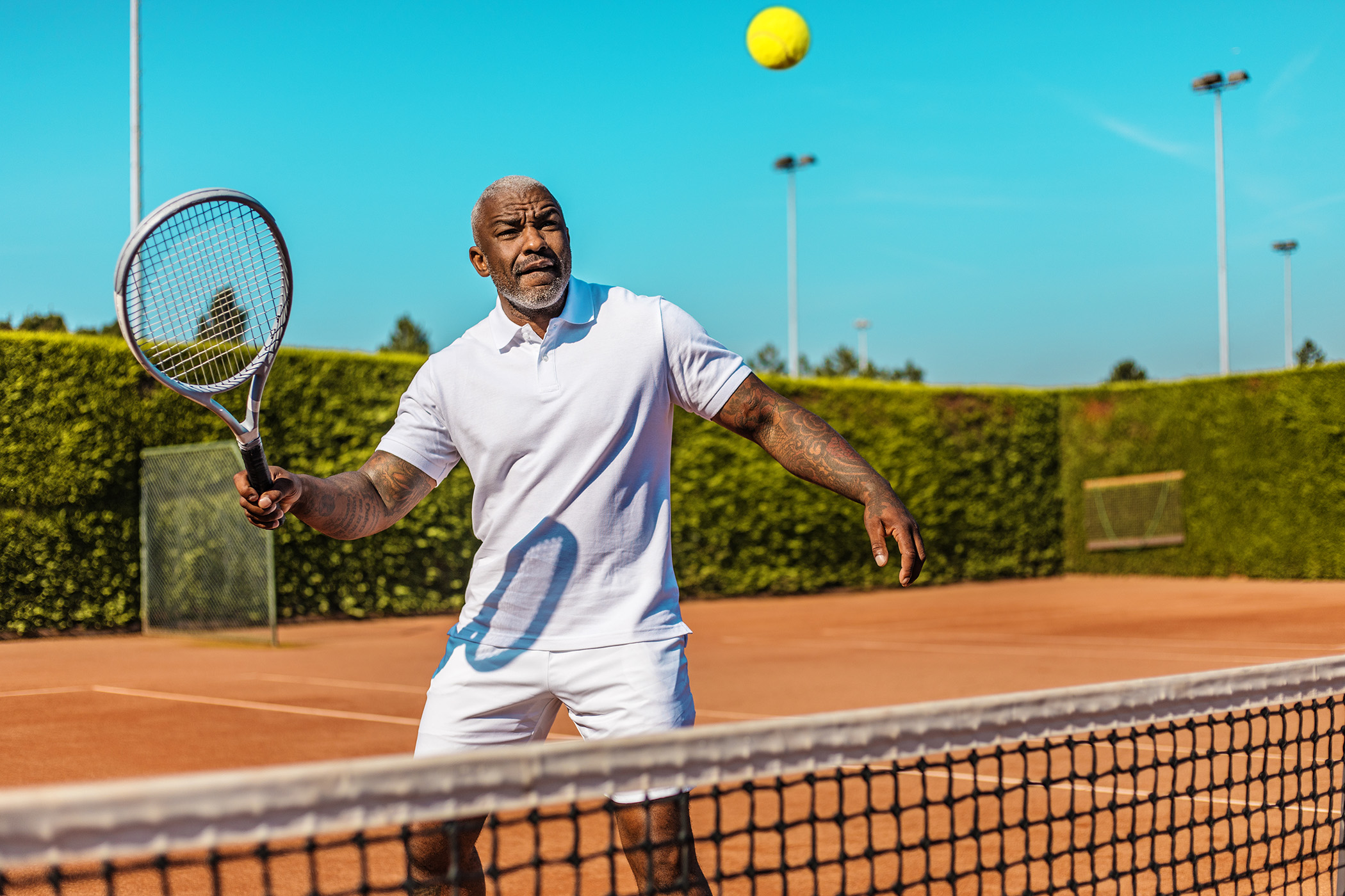 older man playing tennis on a sunny day