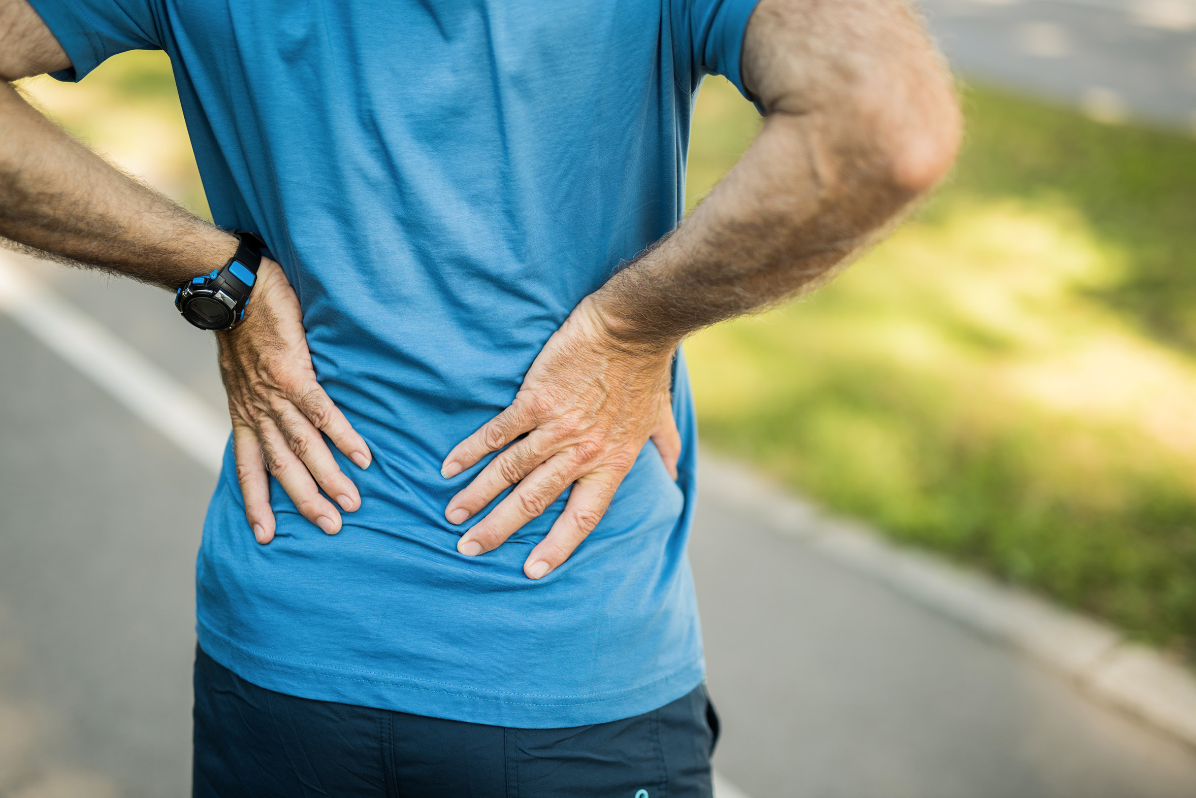 Sporty senior man having a back pain close up.