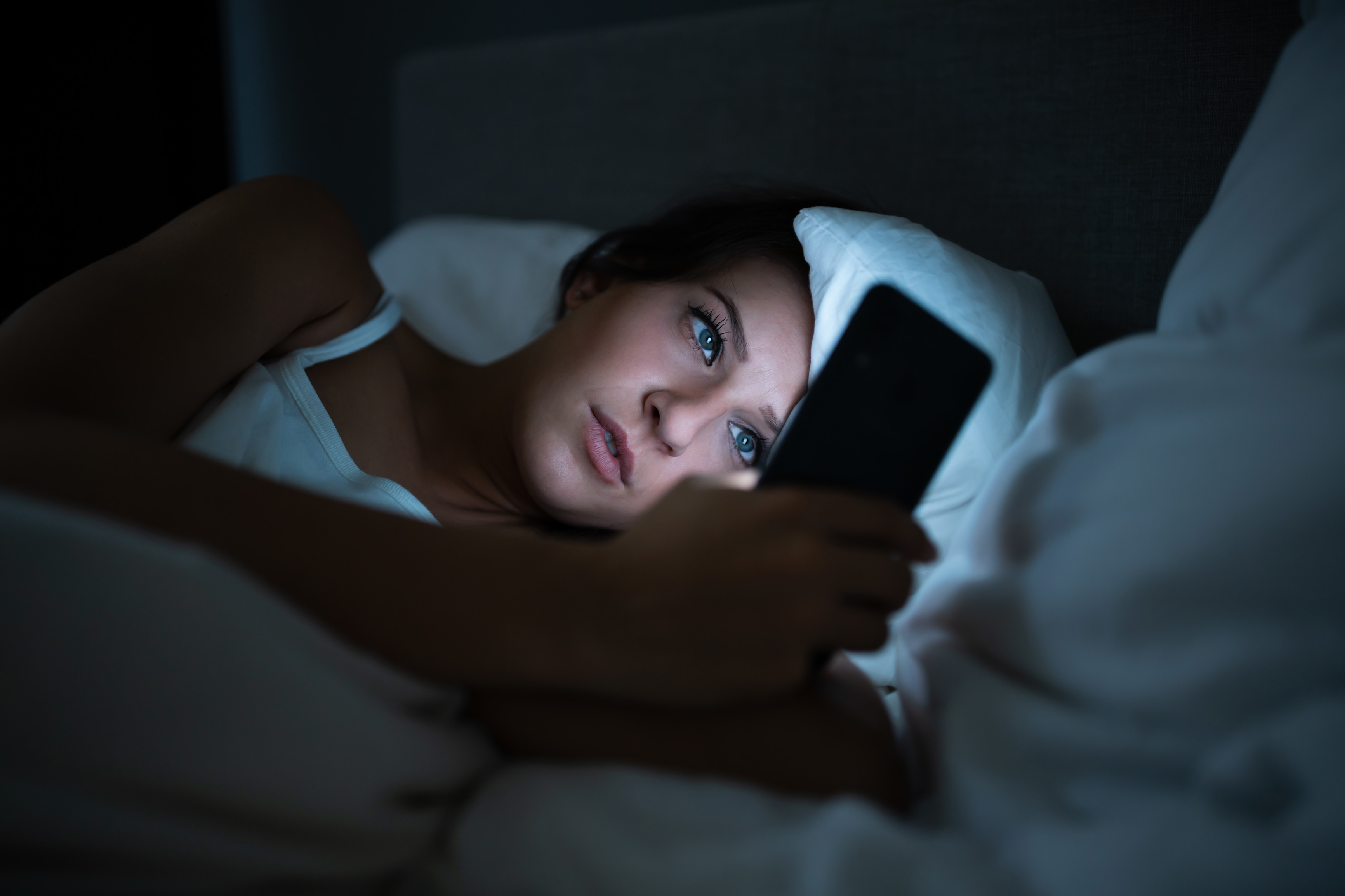 Woman In Bed With Mobile Phone At Night