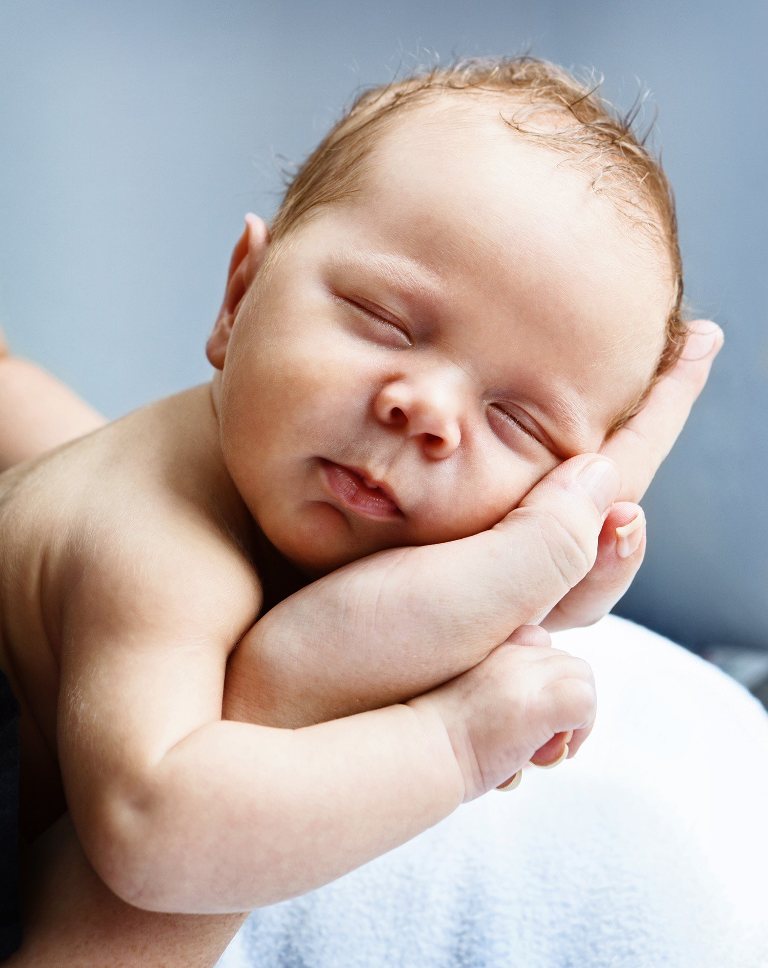 Blissfully sleeping baby cradled in mothers hands stock photo