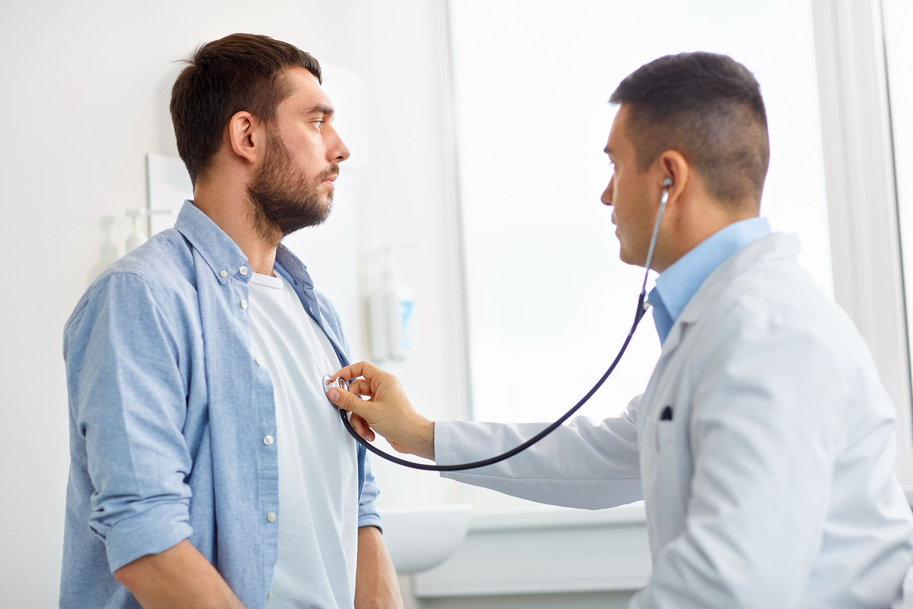 Male patient having his heart listened to by a physician