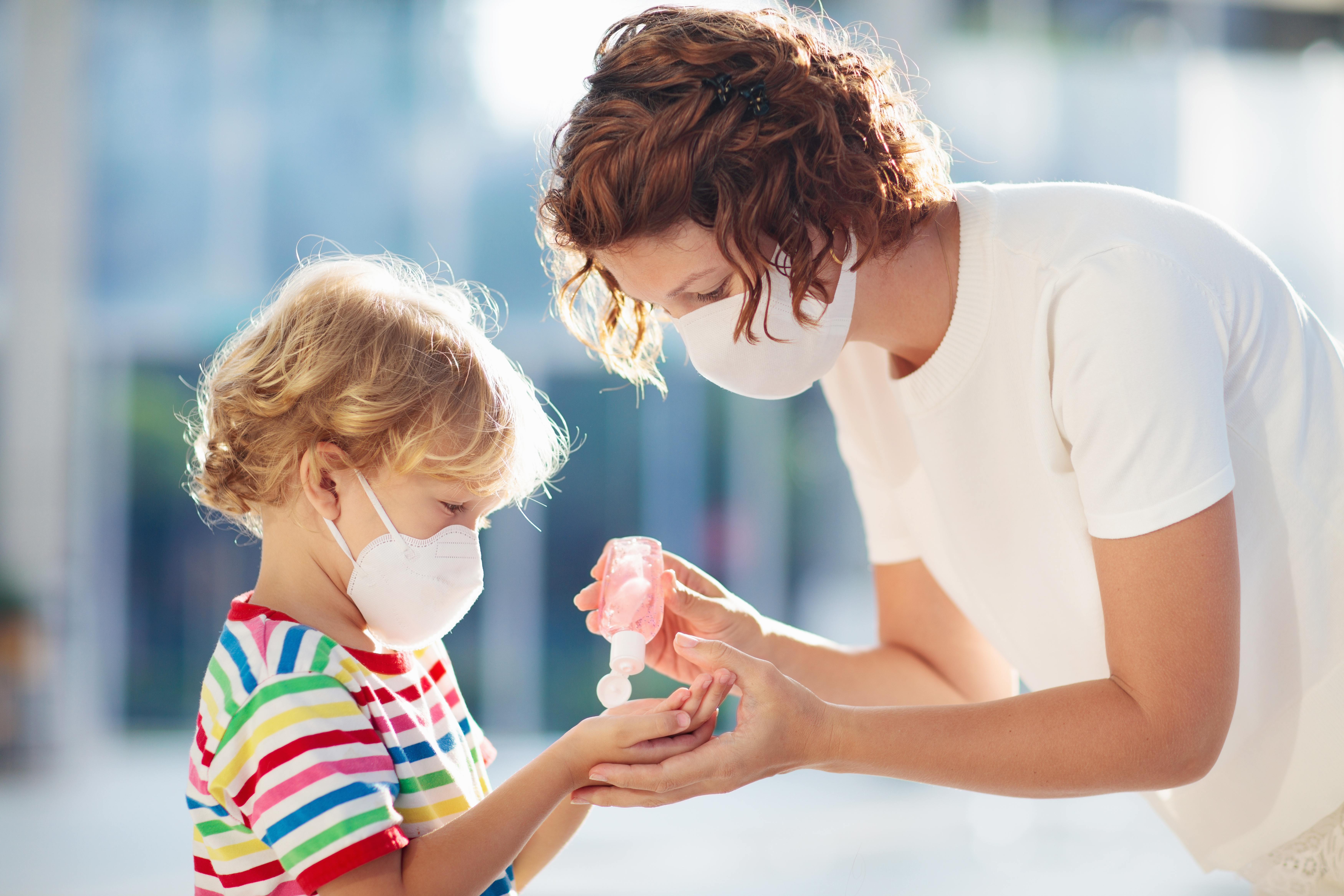 Family with kids in face mask in shopping mall or airport. Mother and child wear facemask during coronavirus and flu outbreak. Virus and illness protection, hand sanitizer in public crowded place.