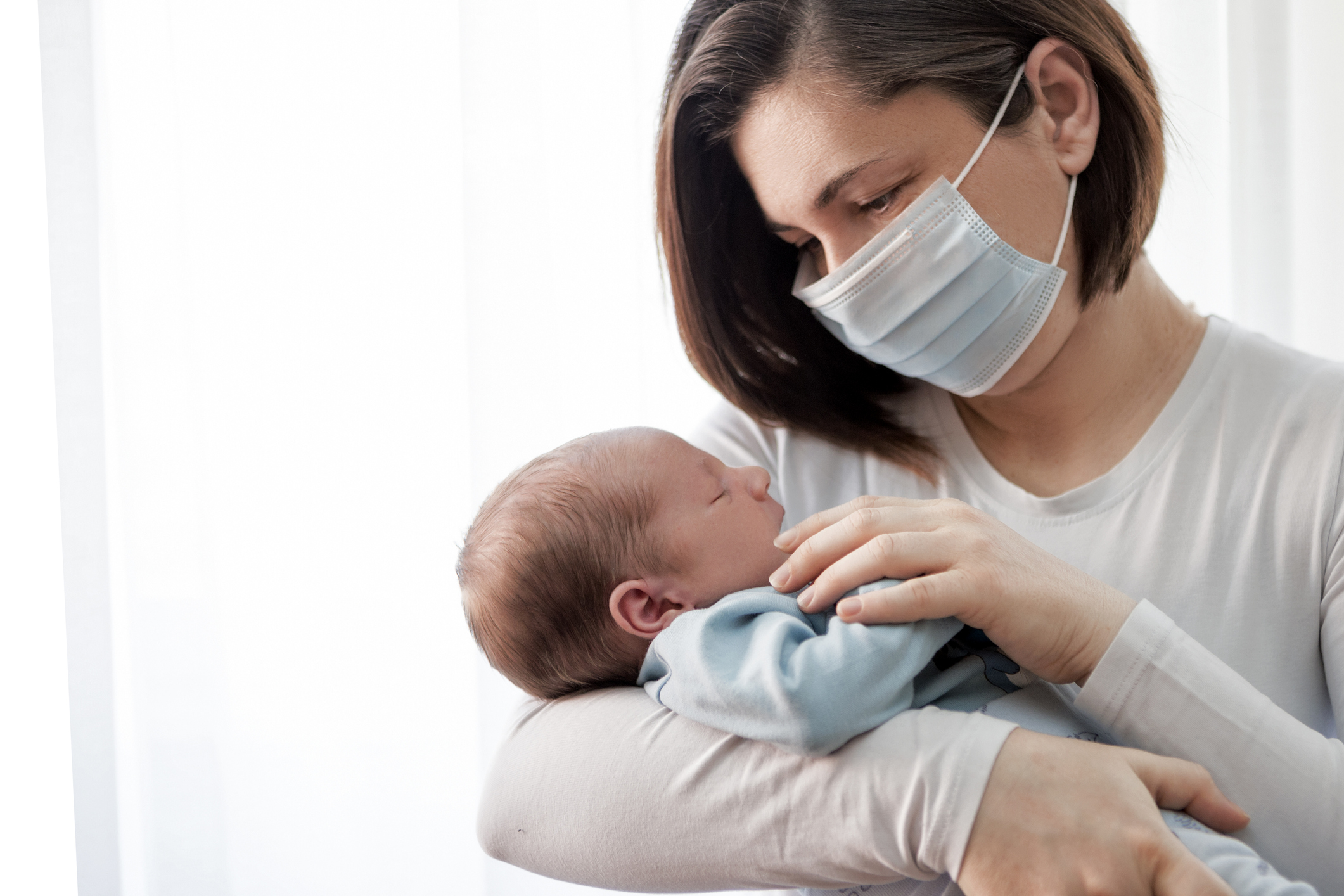 woman in a mask holding an infant