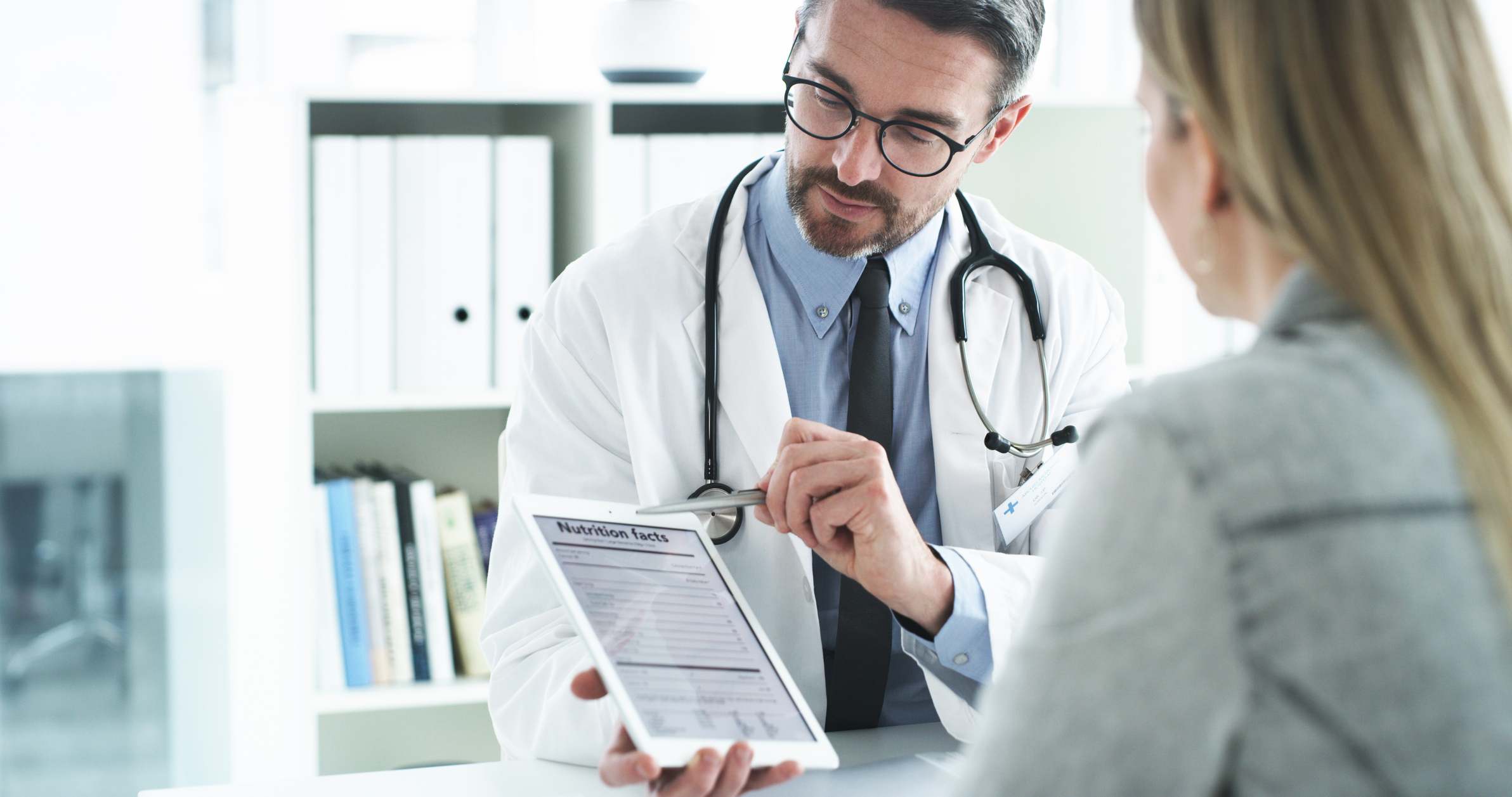 physician showing a patient information on a tablet in a medical office