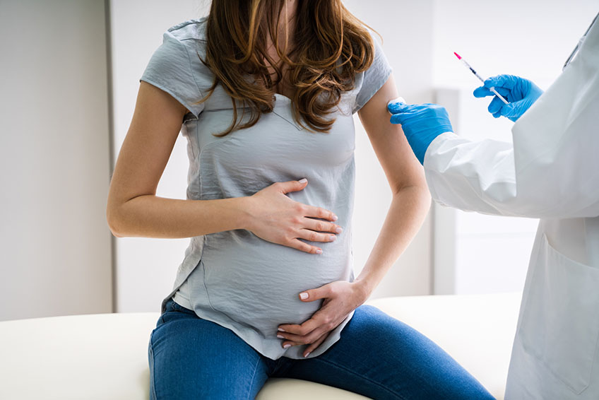 Pregnant woman receiving a vaccine from a physician in a medical office