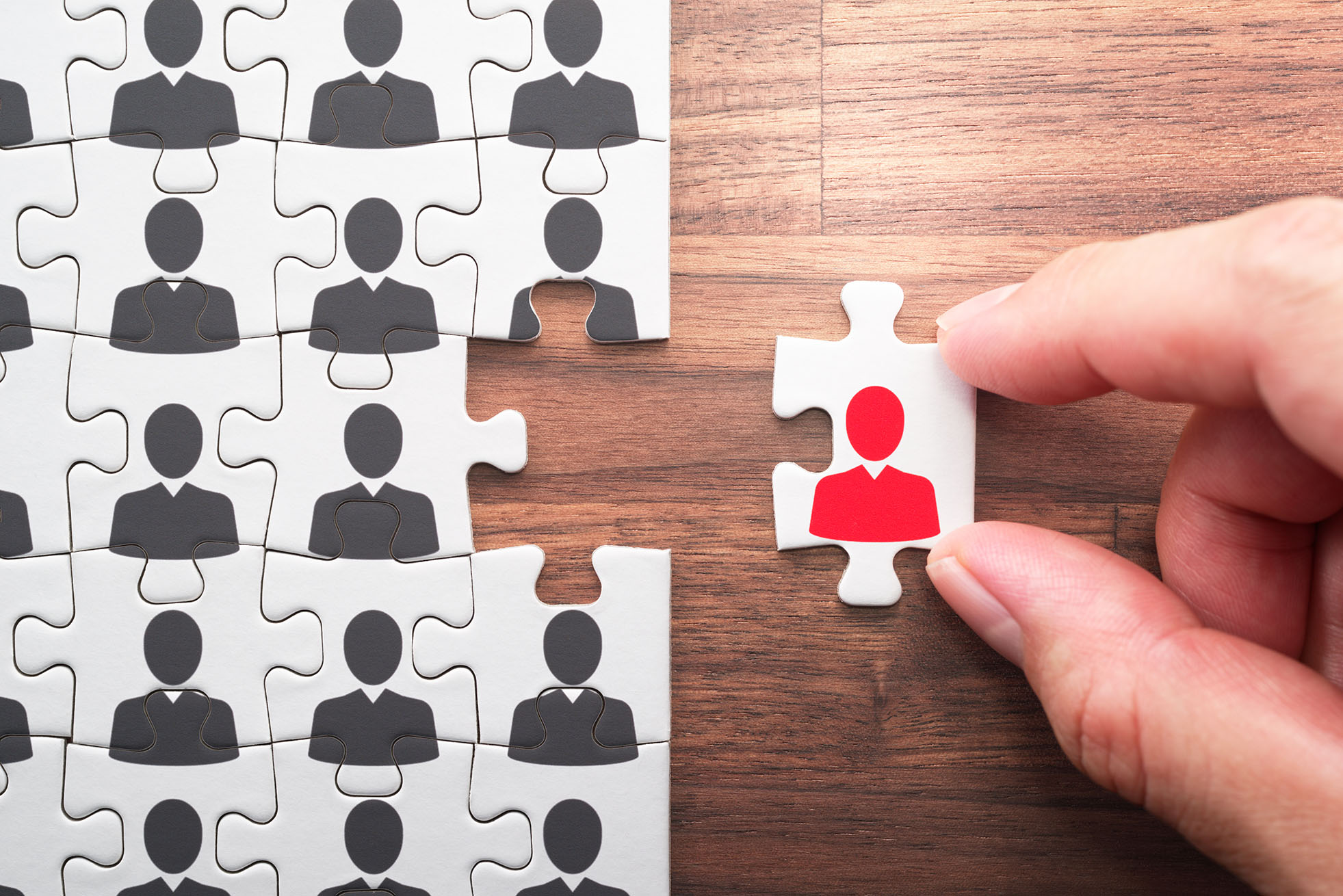 Personnel, employment and recruitment concept. Assembling jigsaw puzzle pieces on wood desk.