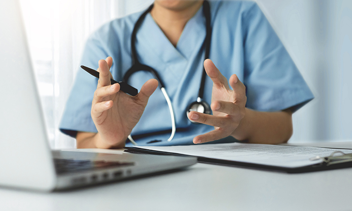 Physician sitting in front of a lap top