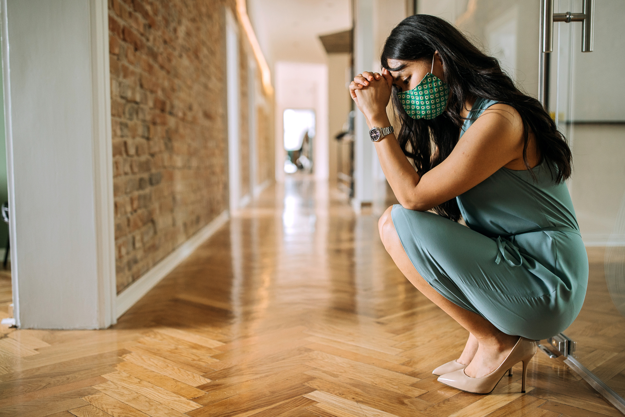 stressed and overworked businesswoman crouching in office hallway