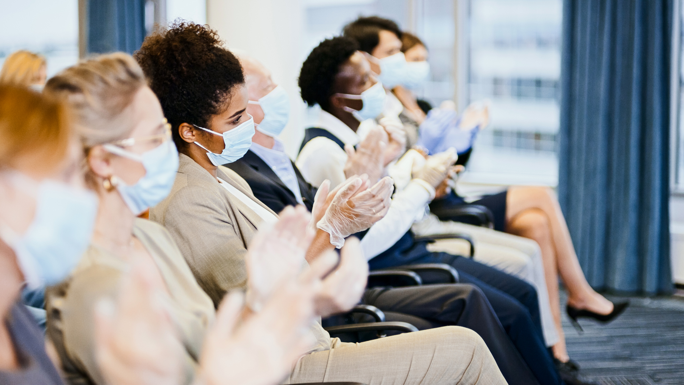 satisfied professionals in protective masks at a conference