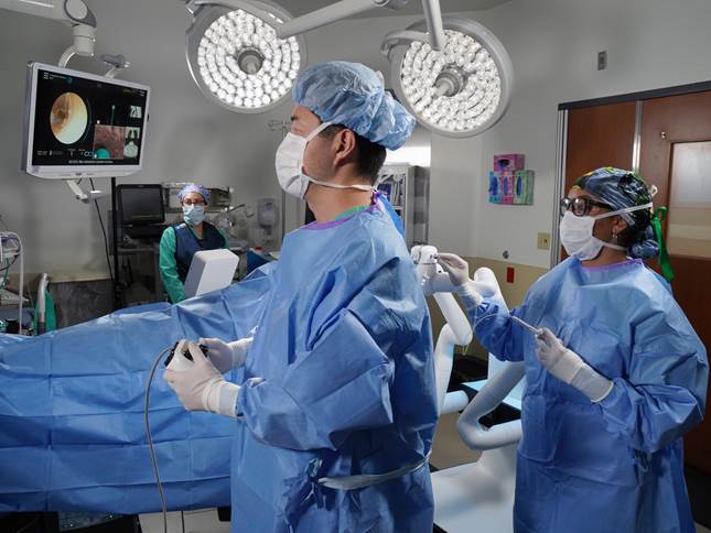 Male and Female Surgeon in blue robes performing surgery