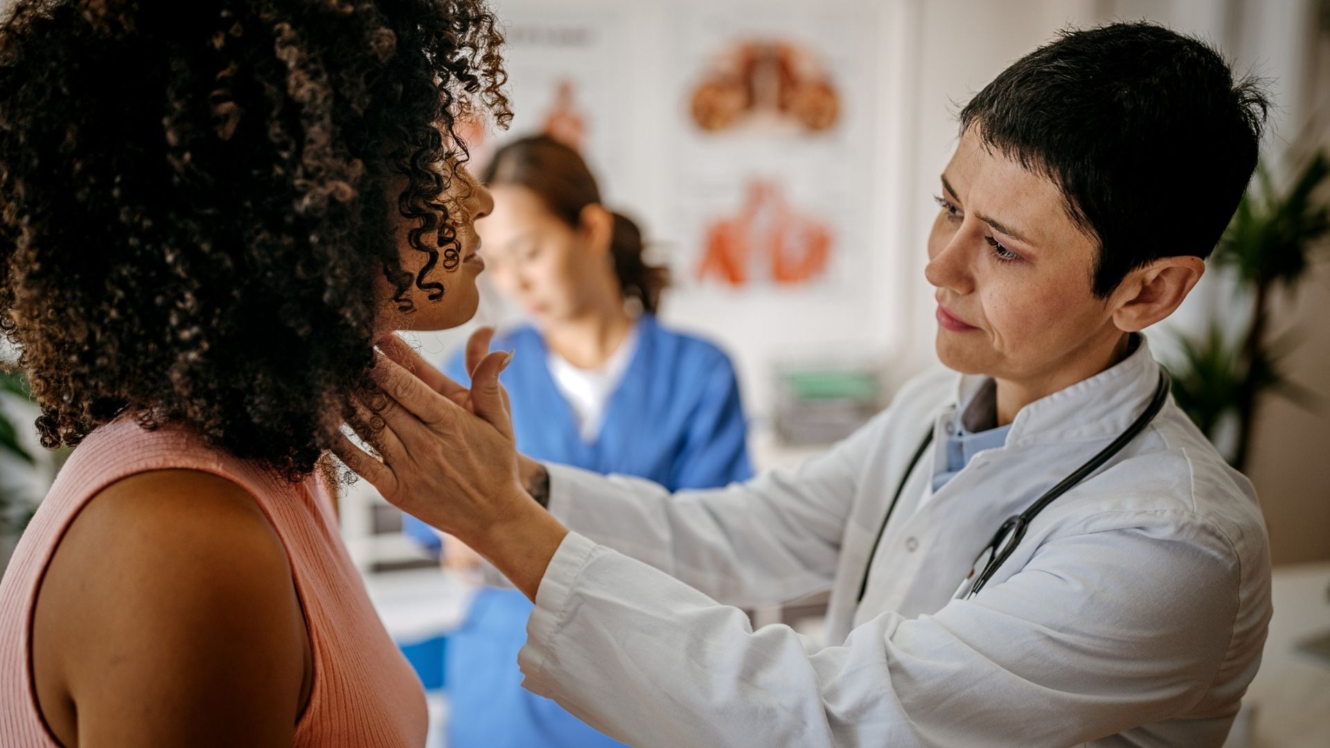 Female doctor checking female patient thyroid
