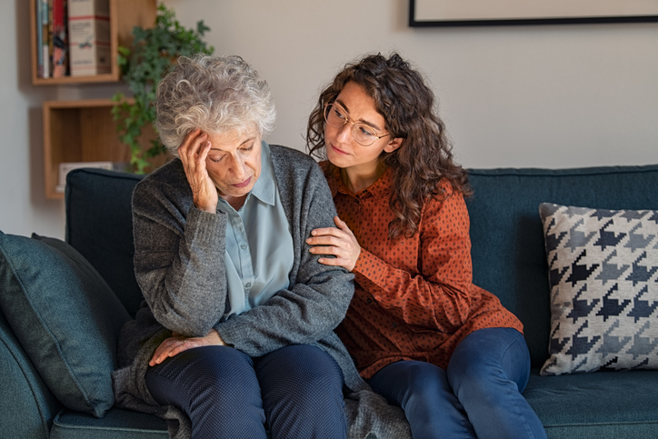 Grandmother holding head, granddaughter consoling her