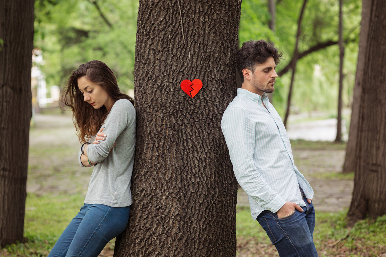 Couple leaning on two sides of the tree trunk