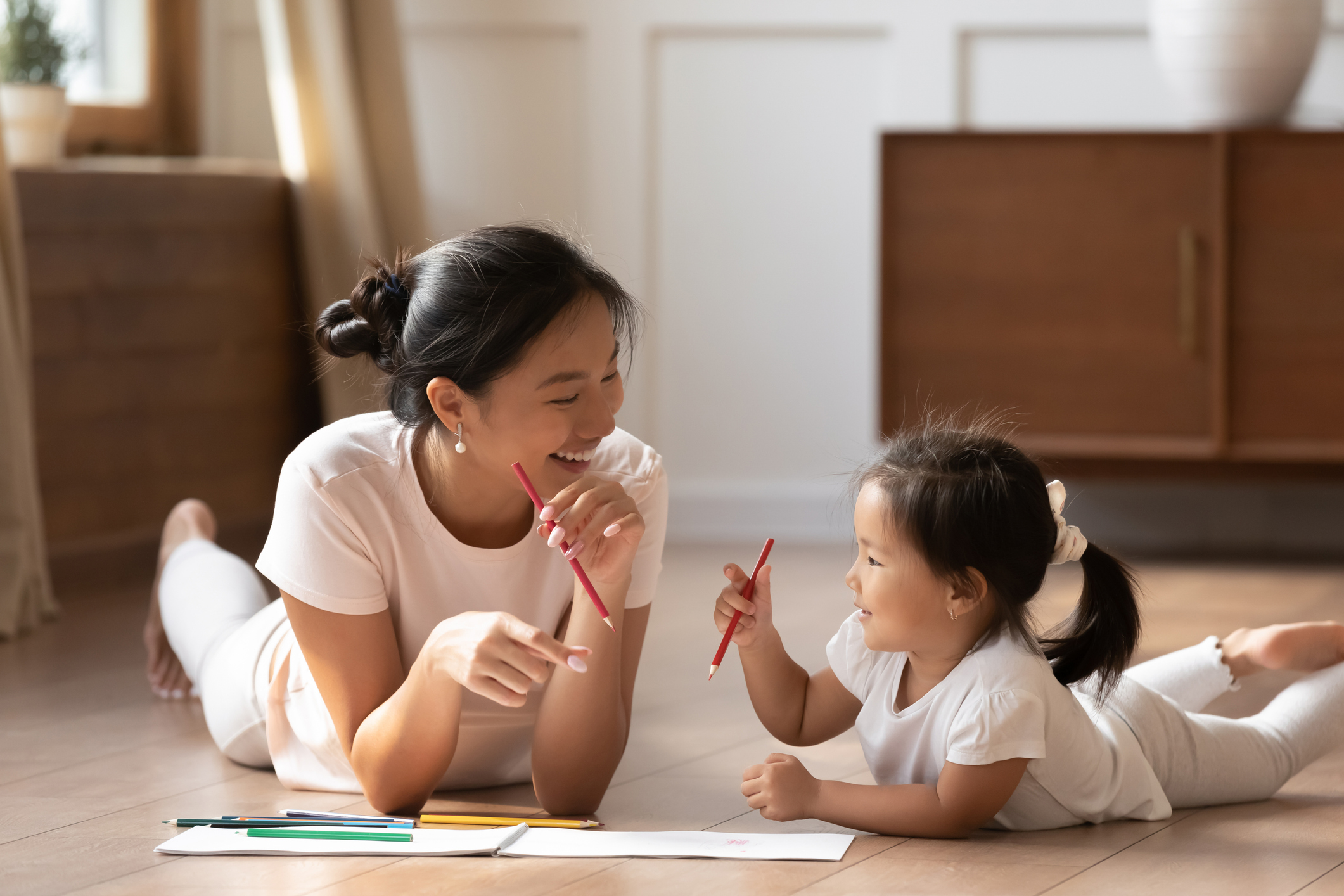 asian mom and daughter lying on floor drawing