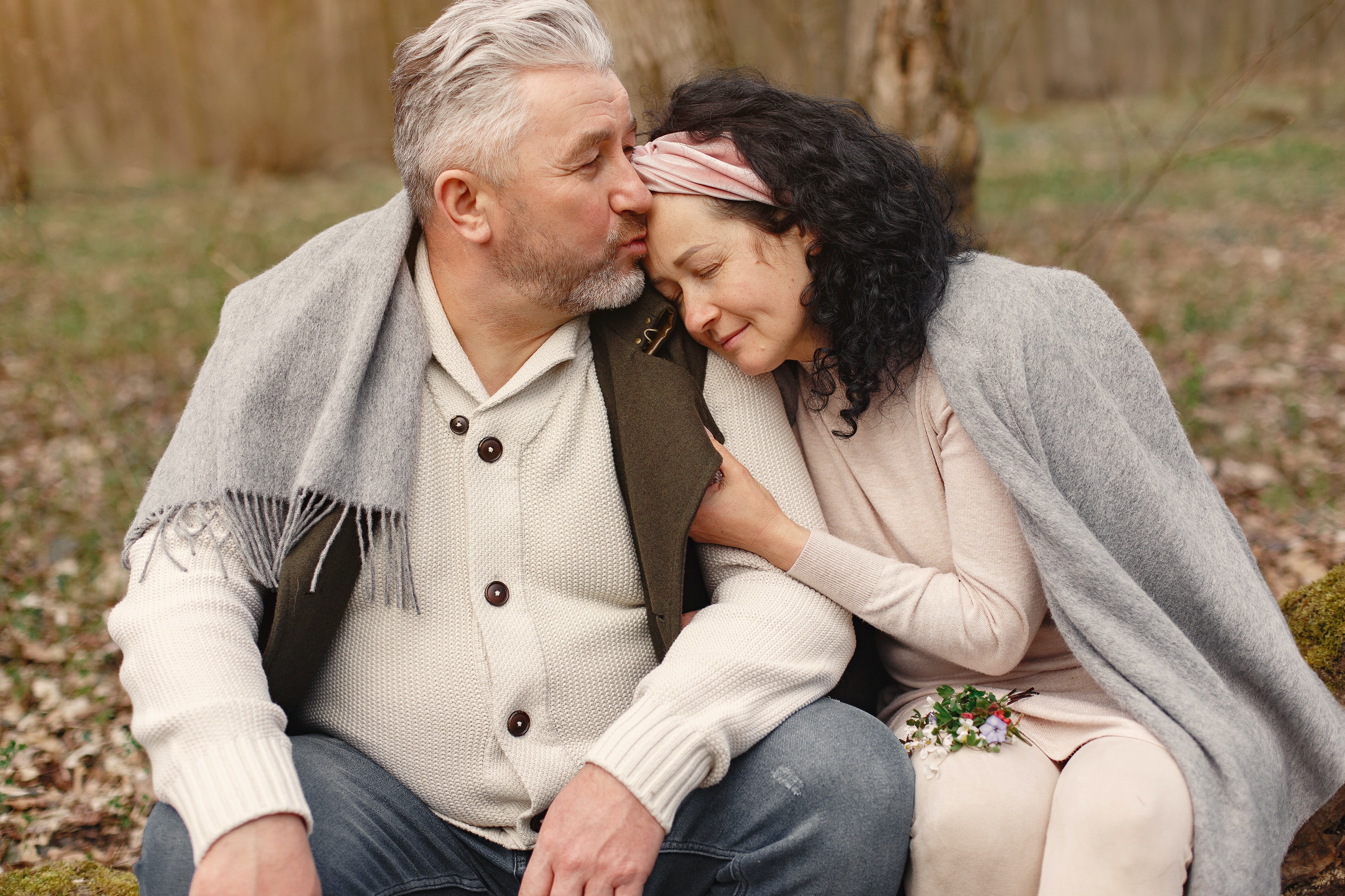 Older man kissing women's forehead in park