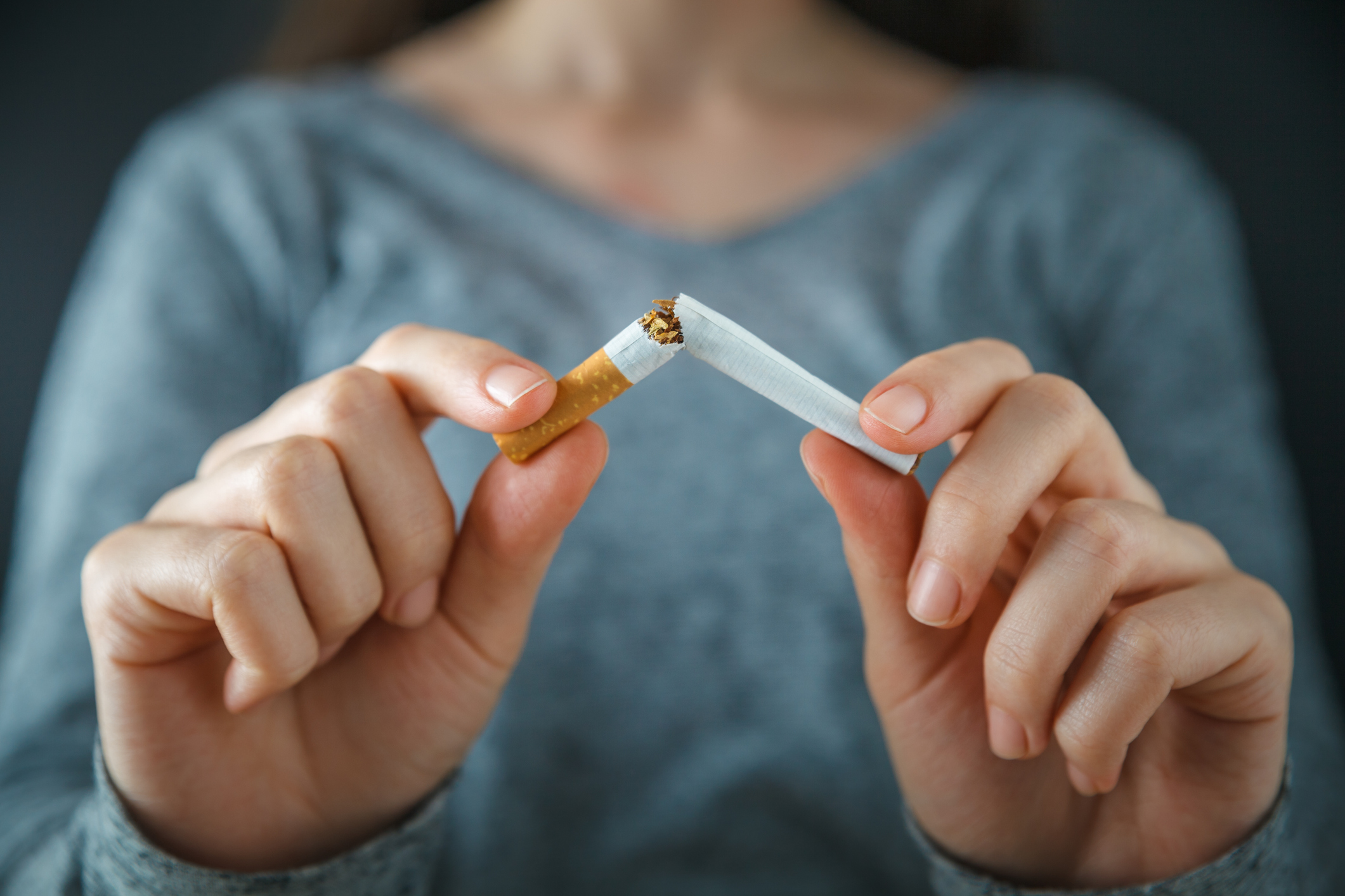 person breaking cigarette in half