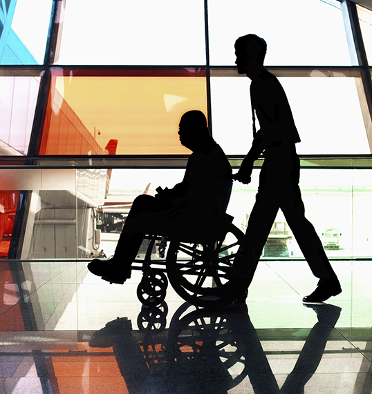 Man in wheelchair being assisted by staff member in facility, side view, full length, shadow, focus on shadow, digital composite stock photo