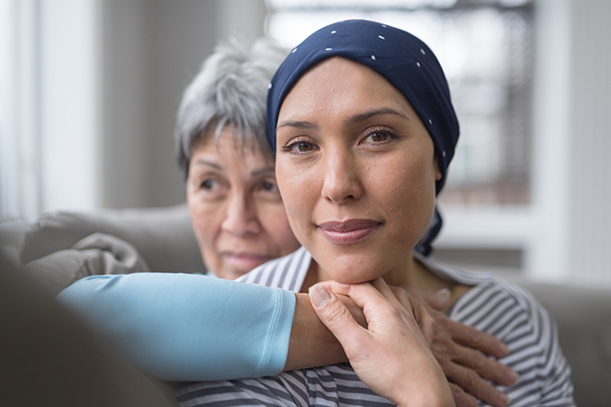 older woman hugging younger woman with a scarf on her head