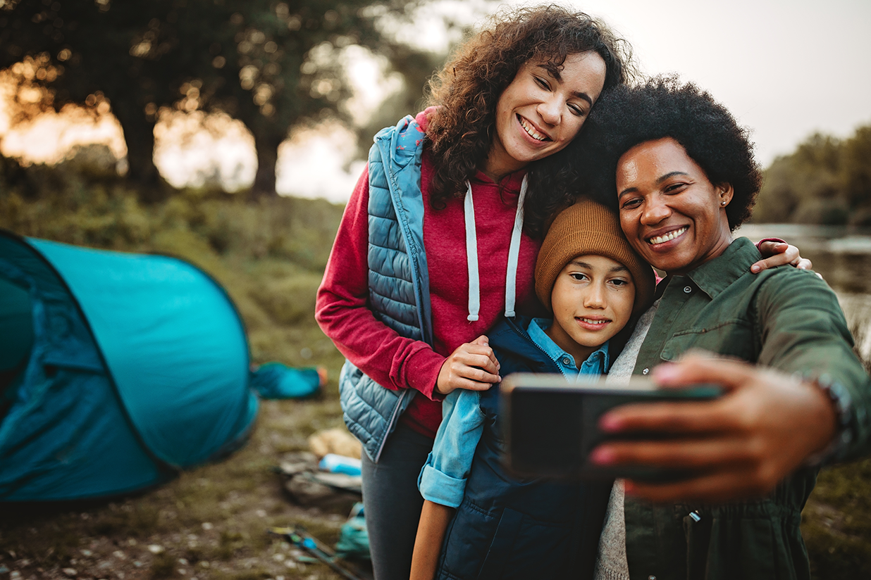 Happy family of three taking selfie near their camping spot