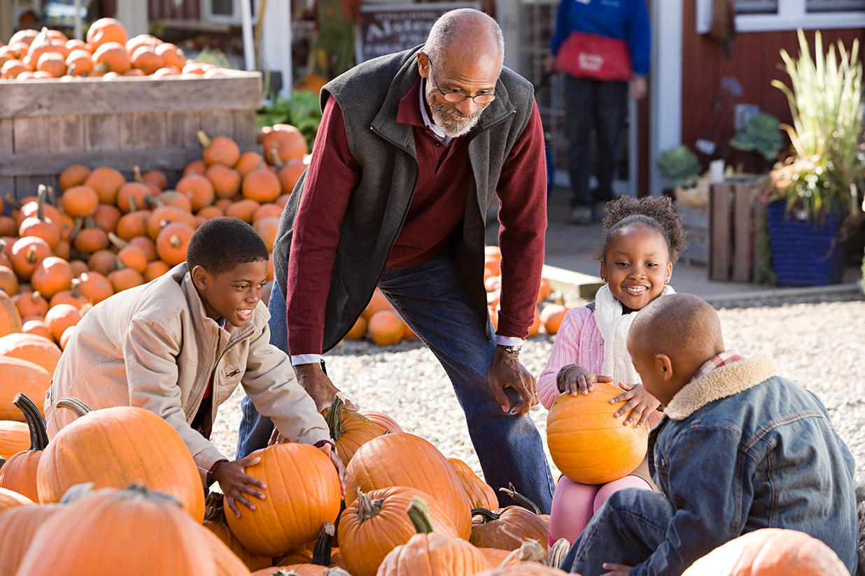 A grandfather and his grandchildren choosing pumpkins