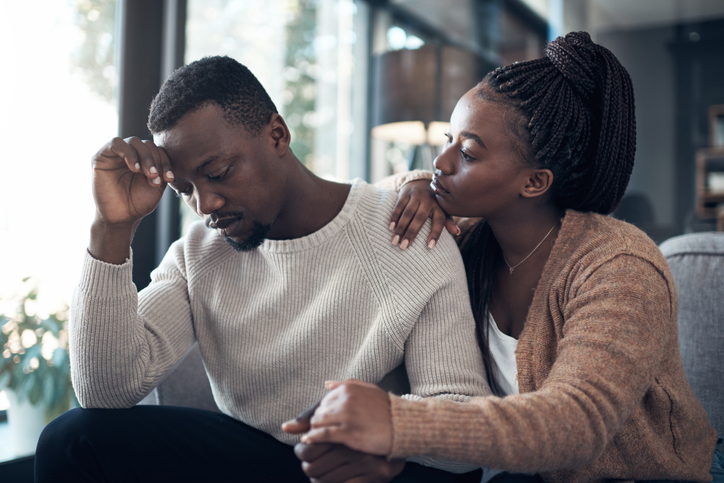 Sad young man being comforted by woman