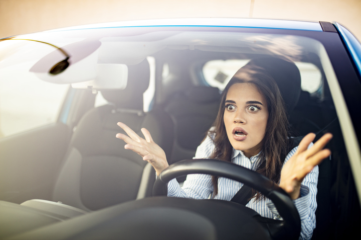 Woman is driving her car very aggressive and gives gesture with her fist. Angry female driver.