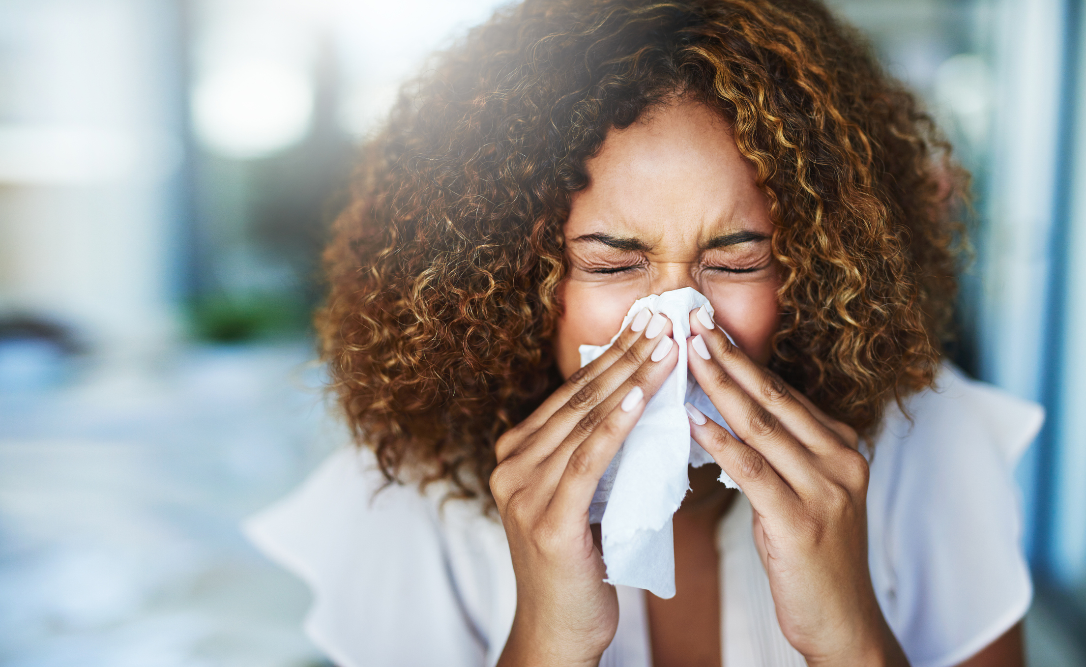 woman sneezing into a tissue