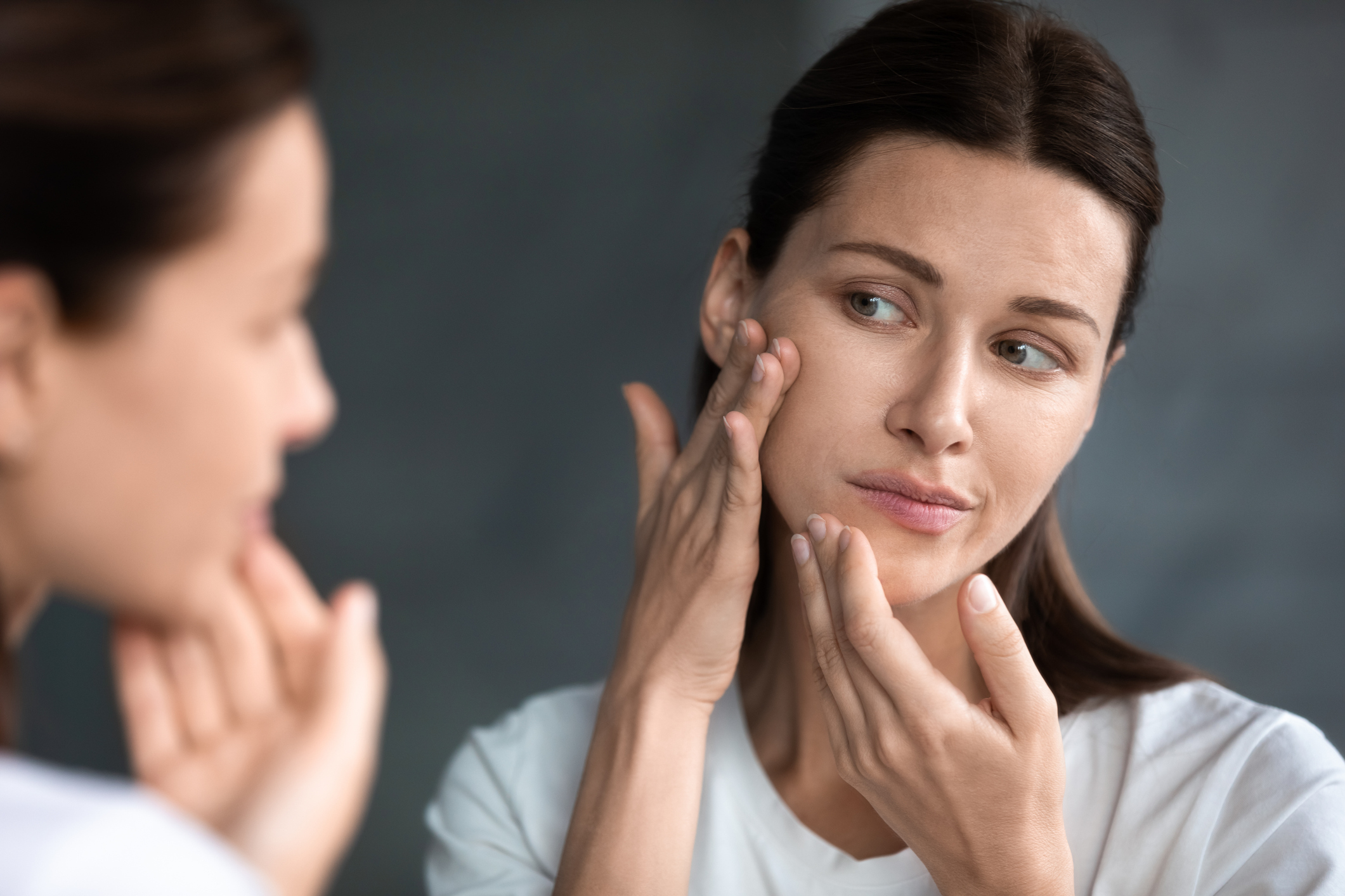 woman checking her skin in mirror