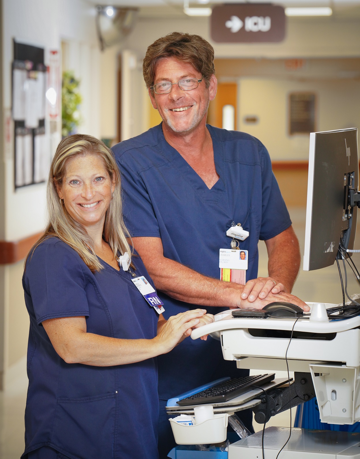 Two hospital nurses working at a work station.