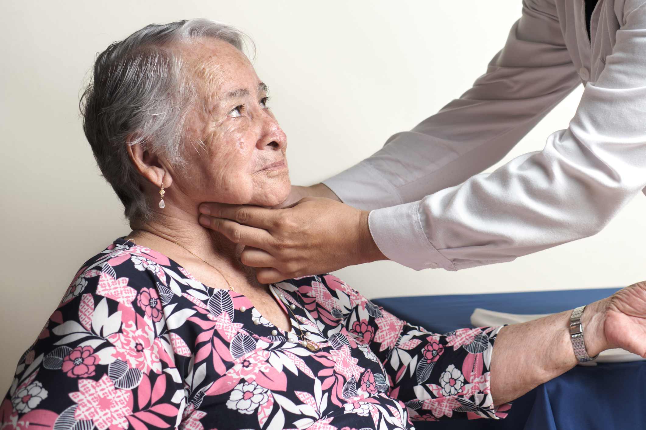 Physician examining carotid pulse of elderly woman