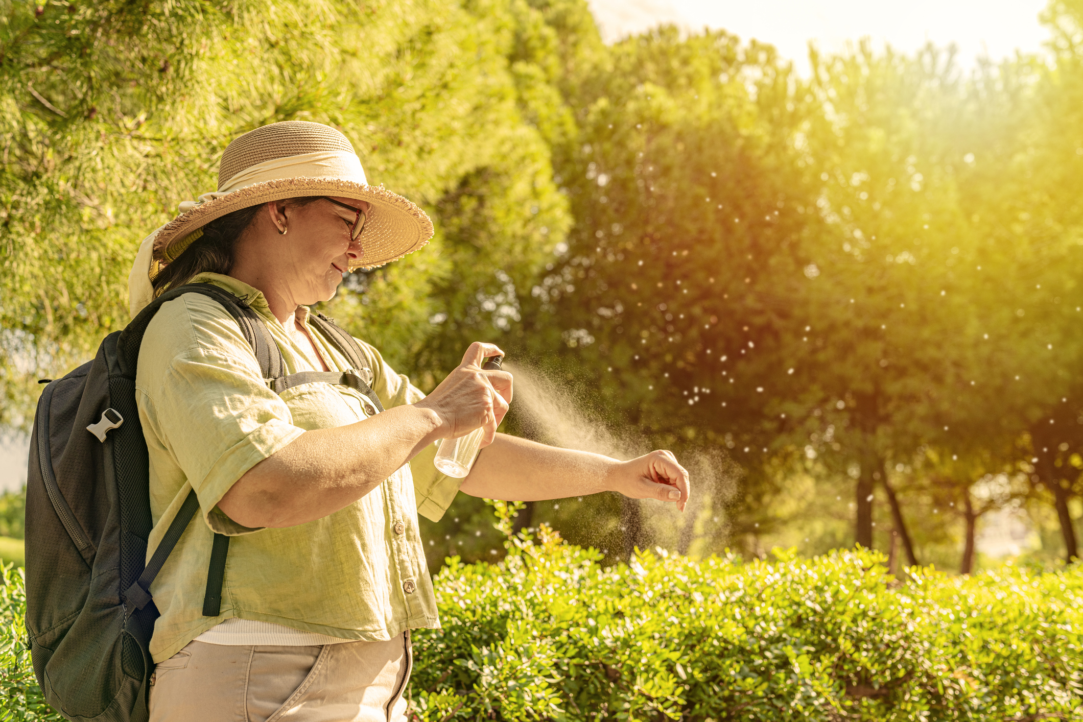Woman applying insect repellent on her arm while hiking