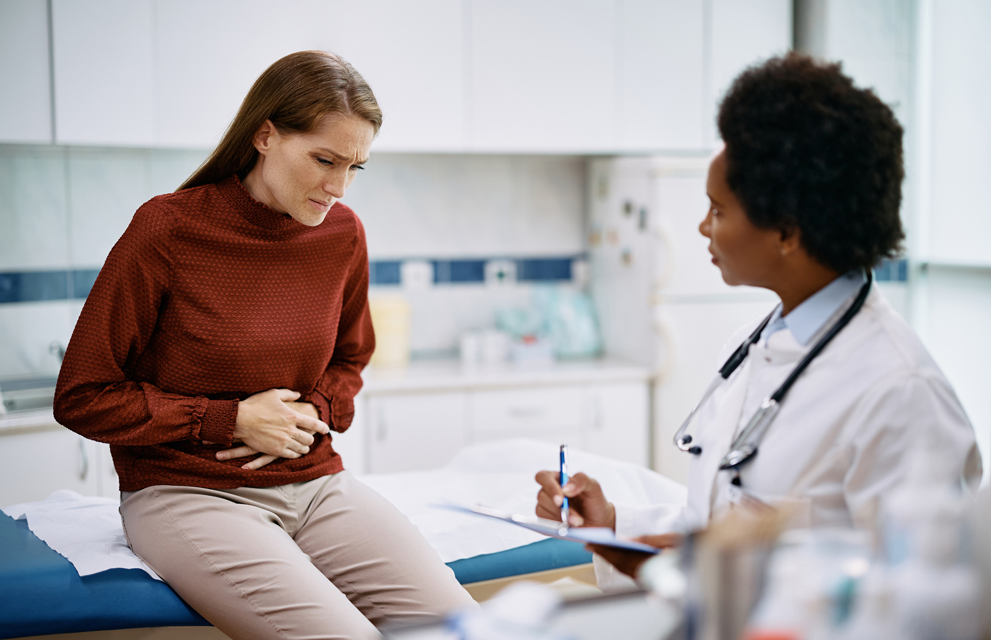 female patient with stomach pain talking to doctor