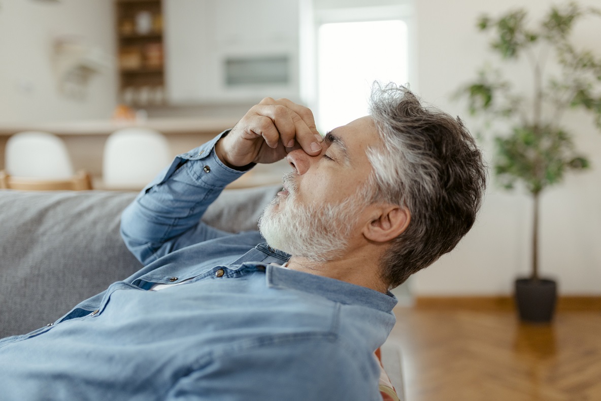Man sitting on sofa holding head