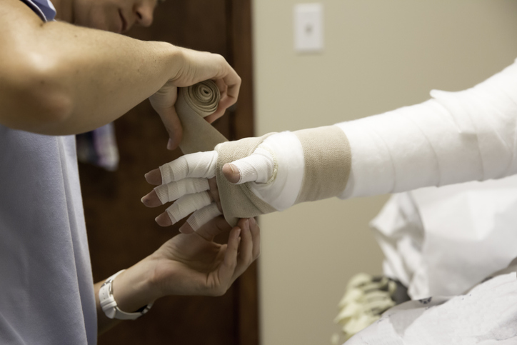 Doctor putting bandage on patient arms